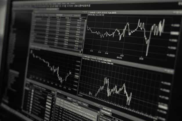 Layar monitor yang menampilkan berbagai grafik dan angka yang mewakili harga saham suatu perusahaan atau aset.