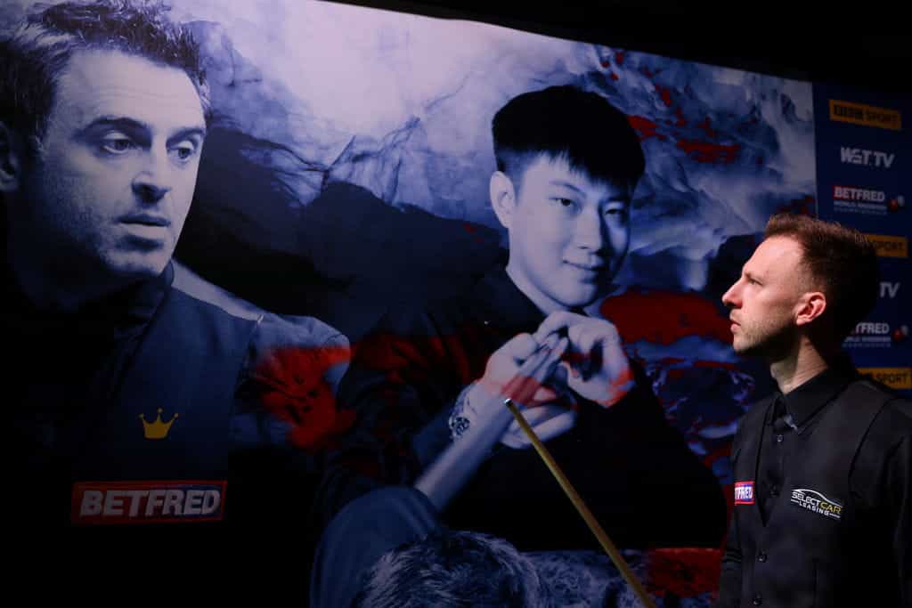 Judd Trump melihat ke arah poster Ronnie O'Sullivan sebelum memasuki teater selama final Kejuaraan Snooker Dunia 2022. 