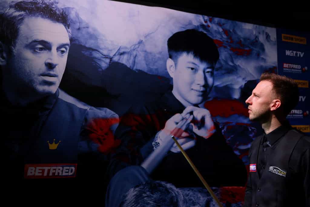 Judd Trump looks towards a poster of Ronnie O'Sullivan before entering the theatre during the 2022 World Snooker Championship final.