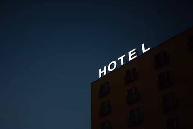 A lit outdoor sign reads HOTEL, on top of a building at night.