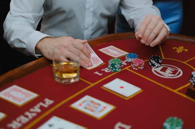 Seseorang bermain poker di kasino dengan kartu dan chip.