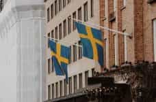Two Swedish flags hanging at an angle from the front of a building.