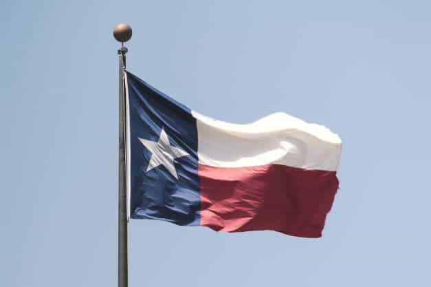 The Chilean flag waves on a flagpole against a blue sky.