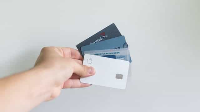 Sebuah tangan memegang tiga kartu kredit.