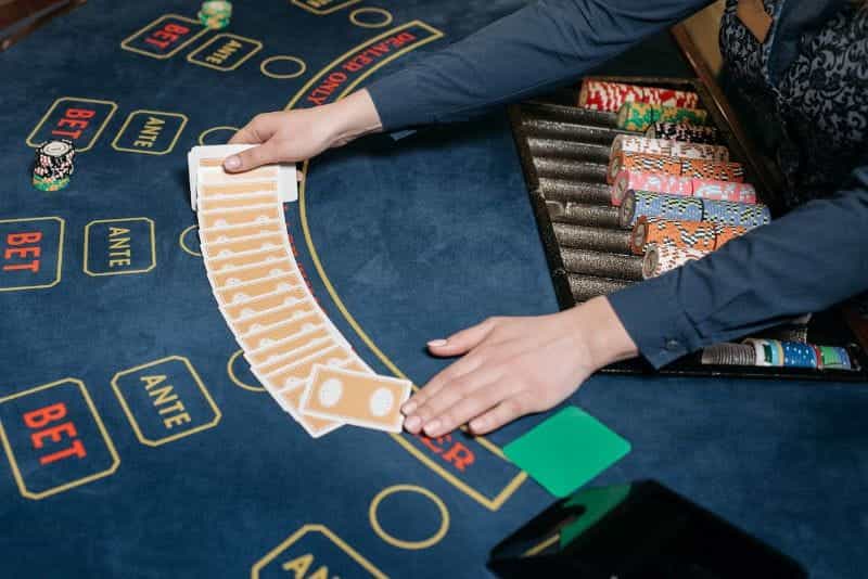 Seorang bandar menangani kartu dan chip poker di kasino.