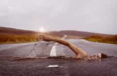 A swimmer swimming through a paved, empty road.