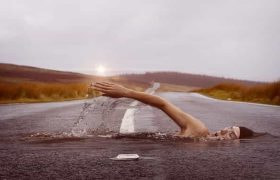 A swimmer swimming through a paved, empty road.