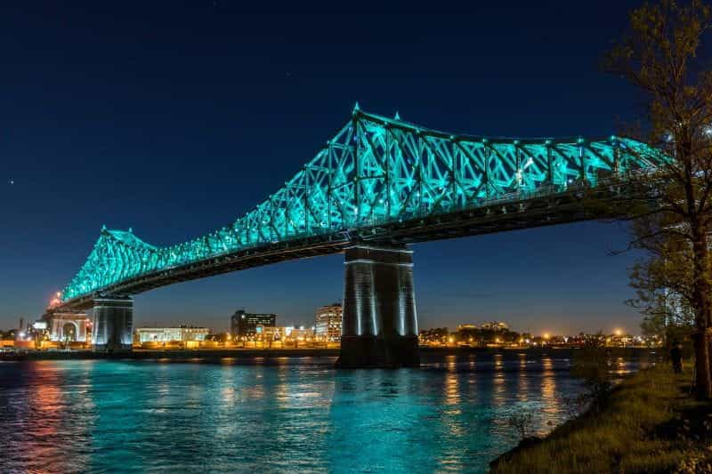 The Jacques Cartier Bridge in Montreal lit neon blue in the evening.