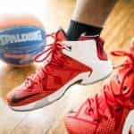 The feet of a basketball player with red basketball shoes.
