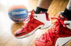 The feet of a basketball player with red basketball shoes.