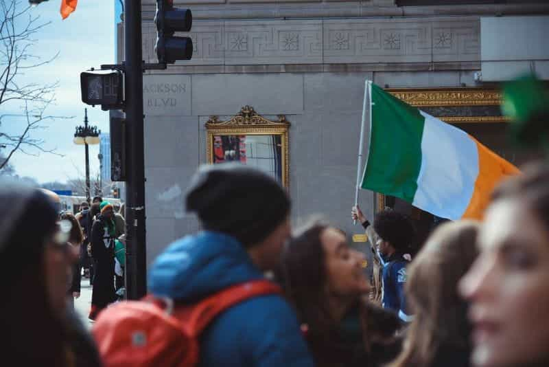 Seorang pria memegang bendera Irlandia di tengah kerumunan.