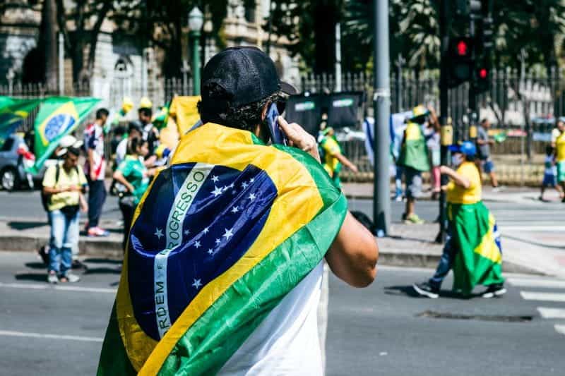 Para pengunjuk rasa mengenakan bendera Brasil di punggung mereka.
