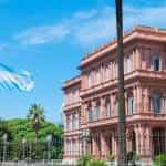 A pink government building in Buenos Aires, behind an Argentine flag.