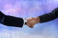 Two peoples’ arms in business suits shaking hands.