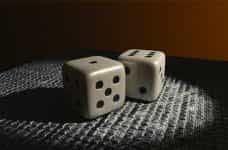 A pair of six-sided white die sitting on a corrugated surface.