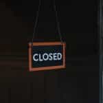 A sign that says CLOSED hangs in a shop window.