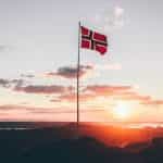 A Norway flag on a flagpole at dusk.