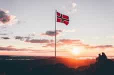 A Norway flag on a flagpole at dusk.