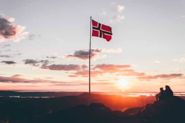 Bendera Norwegia di tiang bendera saat senja.