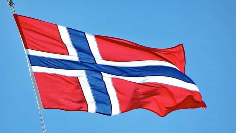A Norway flag against the backdrop of a blue sky.
