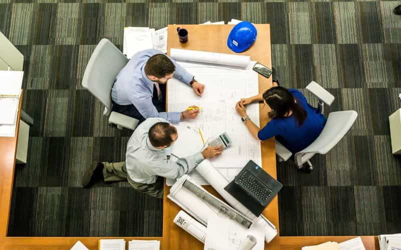 Tiga orang di kantor bekerja.