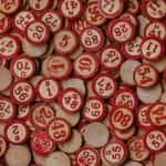 Circular, wooden bingo tokens painted with red numbers lay flat across a table.
