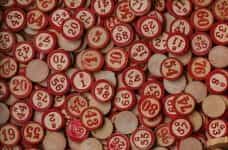Circular, wooden bingo tokens painted with red numbers lay flat across a table.
