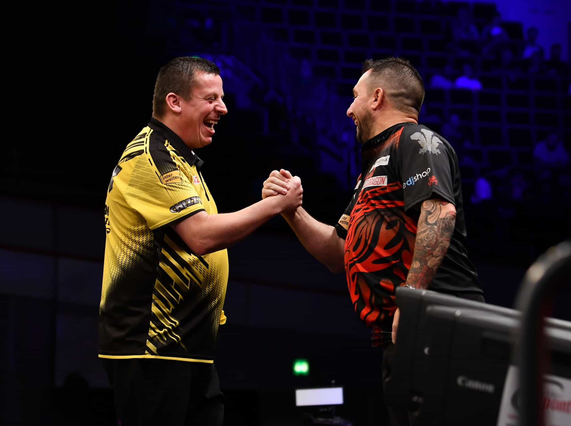 Pemain dart Dave Chisnall dan Jonny Clayton berjabat tangan setelah pertandingan.