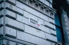 A street sign reads DOWNING STREET SW1 on a corner in London, England.