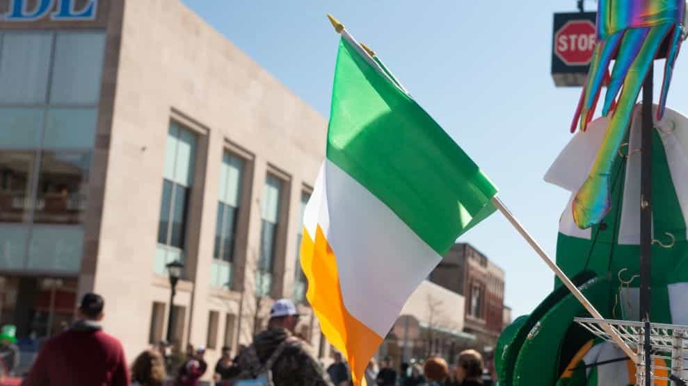 Bendera tiga warna Irlandia melambai dalam pengaturan parade di luar ruangan.