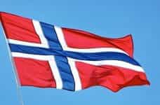 A Norwegian flag flying against a blue sky.