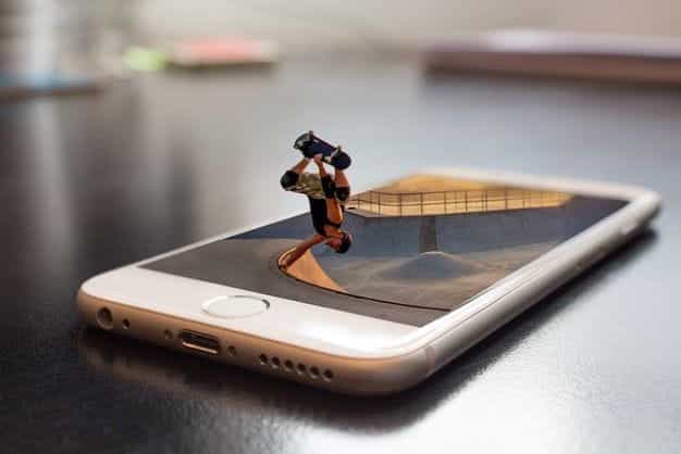 Sebuah smartphone berbaring telentang dengan layar menghadap ke atas, dengan skateboard tiga dimensi muncul dari layar saat melakukan trik.