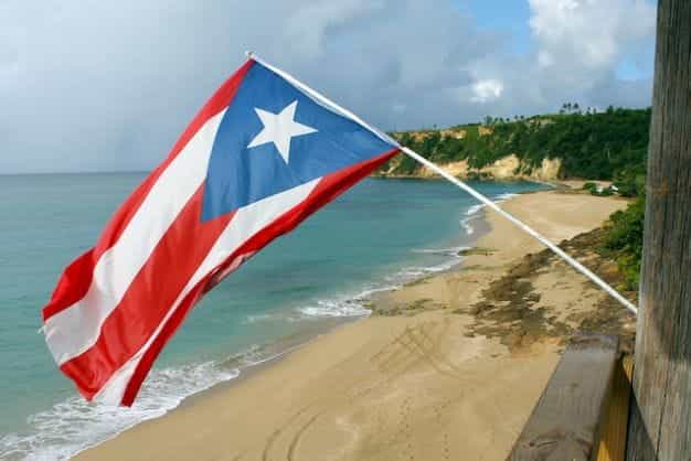 Bendera Puerto Rico melambai di atas pantai.