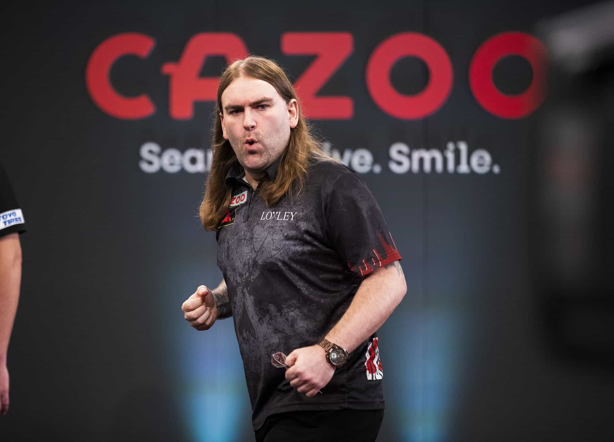 Pemain dart, Ryan Searle, melakukan gerakan tinju setelah mencetak 180.