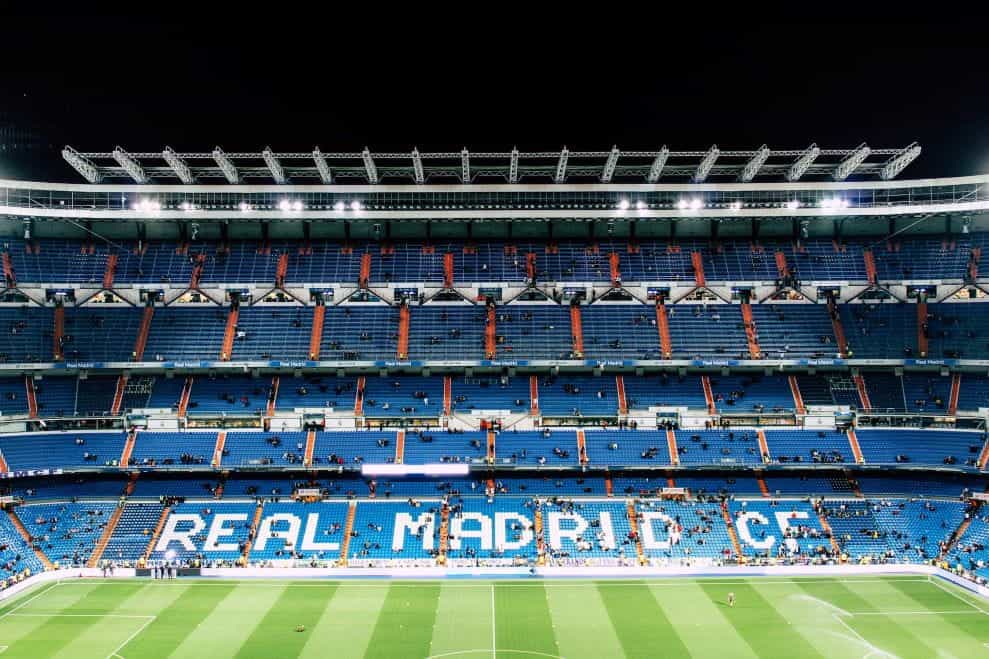Stand di Stadion Santiago Bernabeu, dengan kursi putih bertuliskan Real Madrid CF di tengah lautan kursi biru.