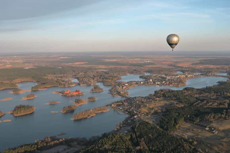 Lanskap Trakai di Lithuania, dengan balon udara panas melayang di atas.