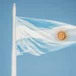 The Argentinian flag waves against a blue sky.