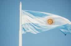 The Argentinian flag waves against a blue sky.