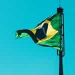 The Brazilian flag waves against a blue sky.