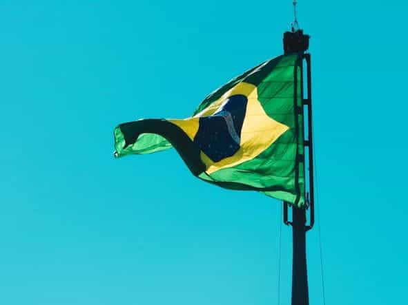 Bendera Brasil berkibar di langit biru.