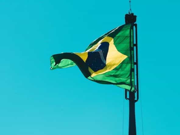 Bendera Brasil berkibar di langit biru.