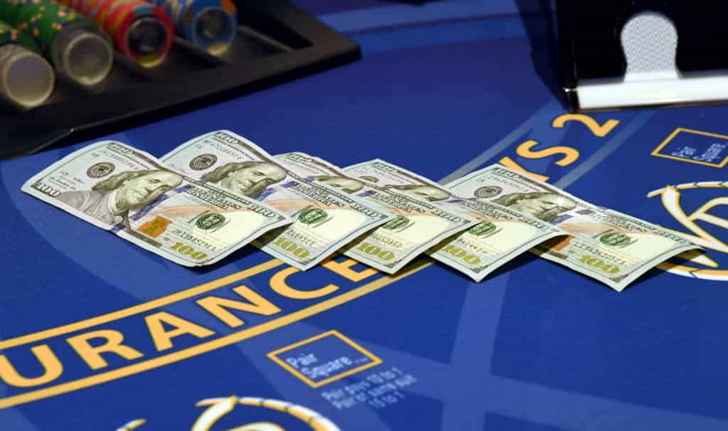 Lima lembar uang $100 diletakkan di atas meja blackjack.