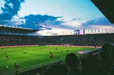 A packed football stadium under floodlights with a live match taking place.