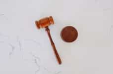 A brown gavel and block combo placed on a white marble top table.
