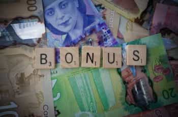 Scrabble tiles spell out the word bonus while being placed on top of currency notes.