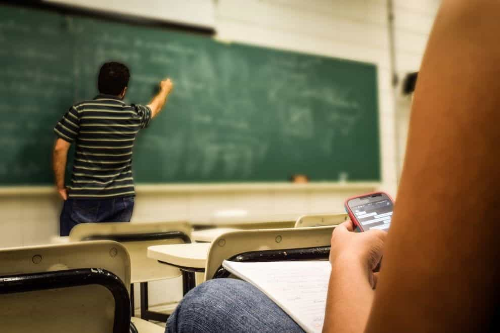 Seorang guru menulis di papan tulis di kelas.