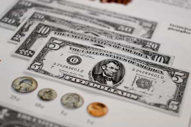 Mata uang kertas USA ditempatkan di samping koin.