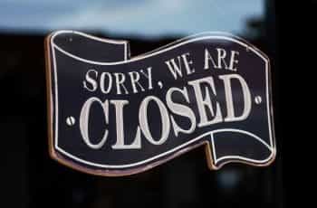 A black and white sign on a glass door reads SORRY WE ARE CLOSED.