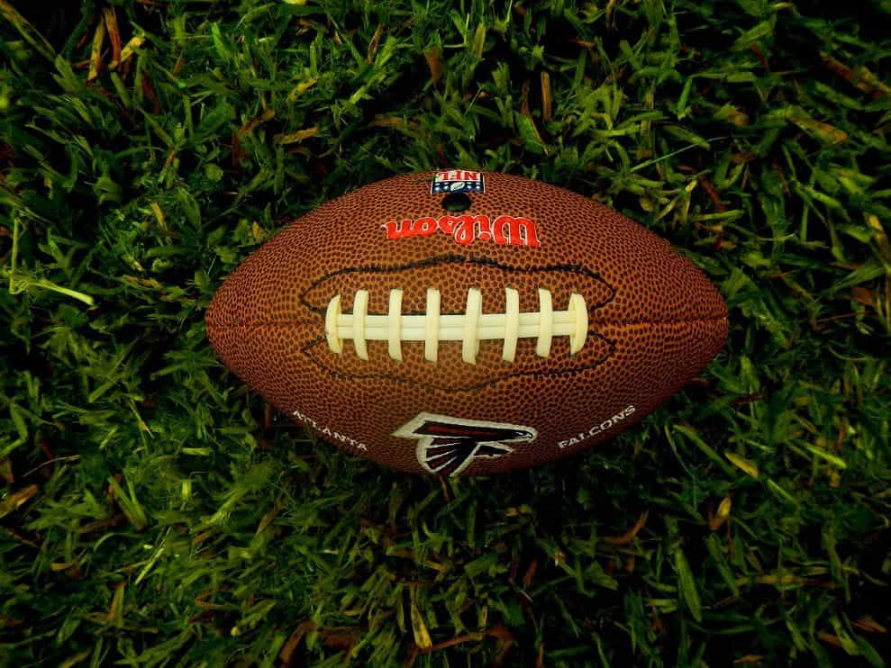 Sepak bola Amerika klasik yang diletakkan secara horizontal di atas rumput lapangan sepak bola.