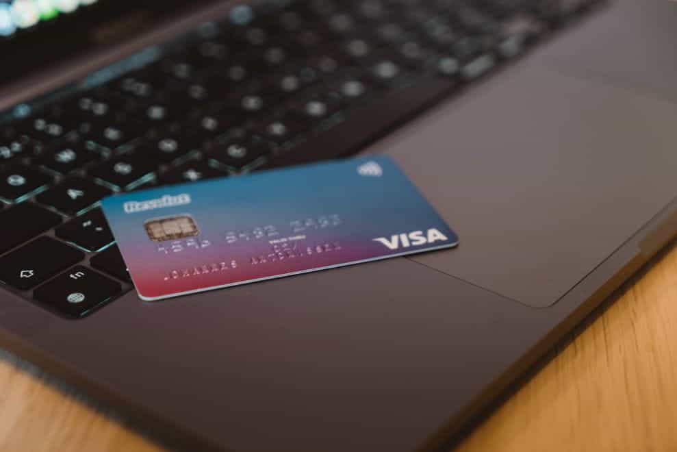 Kartu kredit diletakkan di tepi laptop yang terbuka.